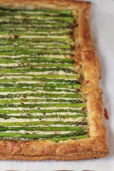 asparagus and cheese tart on top of a white tablecloth with wooden utensils