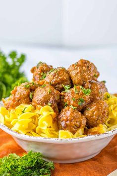 meatballs and noodles in a white bowl with parsley garnish on the side