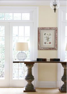 a living room with two lamps on either side of the table and an art piece hanging above it