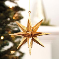 a gold star ornament hanging from a christmas tree