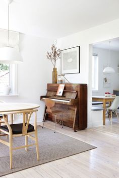 a living room with a piano, table and chairs