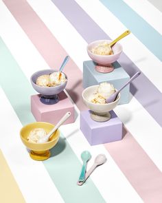 three bowls with ice cream and spoons on colorful striped tablecloth next to each other