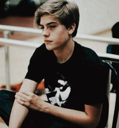 a young man sitting on top of a wooden chair