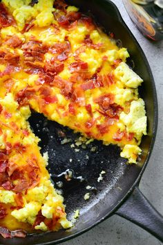 an omelet with bacon and cheese is in a skillet on the table