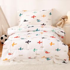 a child's bed with airplanes on it and a teddy bear next to it