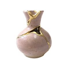 a pink vase with gold leaf decoration on the top and bottom, against a white background