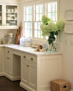 a kitchen filled with lots of white cabinets and counter top space next to a window