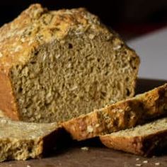 a loaf of bread sitting on top of a cutting board next to two slices of bread