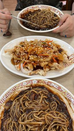 two plates filled with noodles and meat on top of a table next to each other