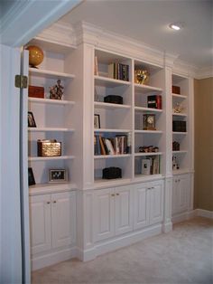 an empty room with white bookcases filled with books