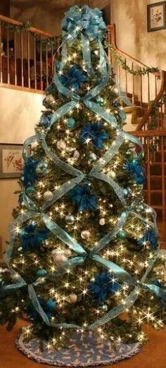 a decorated christmas tree with blue ribbon and lights