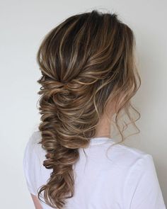 a woman with long hair wearing a white t - shirt and fishtail braid in her hair