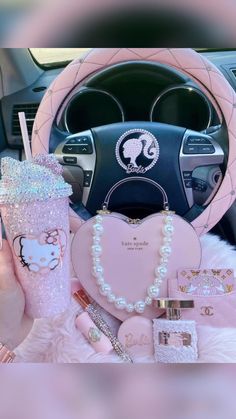 a pink car steering wheel cover with hello kitty on it and other items in front of it