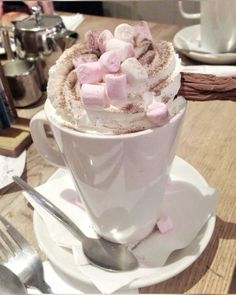 a cup filled with marshmallows on top of a white saucer