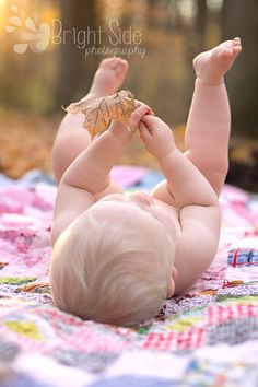 a baby laying on it's back with a leaf in its hand