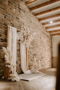 a room with brick walls and white drapes on the ceiling, decorated for a wedding ceremony