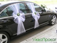 a black car decorated with white ribbons and flowers