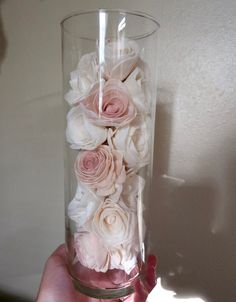 a hand holding a glass vase with flowers in it