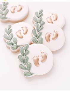 four decorated cookies sitting on top of each other in the shape of leaves and footprints