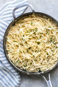 a skillet filled with alfredo sauce on top of a blue and white striped towel