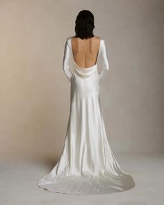 the back of a woman's white wedding dress with long sleeves and open shoulders