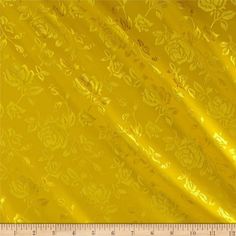 a ruler is next to a yellow fabric with flowers and leaves on it's side