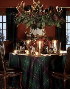 the table is set for christmas dinner with deer antlers and pine cones on it