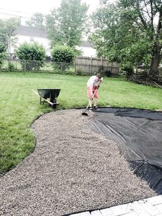 a woman is cleaning the yard with a lawn mower and black tarp over it