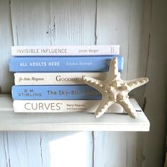 three books are stacked on top of each other, with a starfish sitting between them