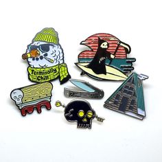 several pins and magnets on a white surface including a skateboarder, skeleton, skull