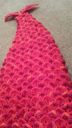 a pink crocheted dress laying on the floor