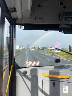 a bus driving down a highway with a rainbow in the background