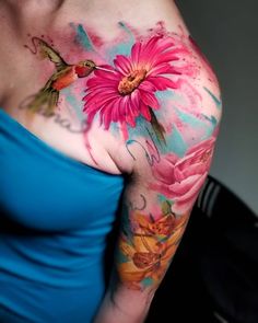 a woman with a flower tattoo on her arm and shoulder is posing for the camera