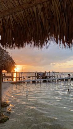 the sun is setting over the water and people are on the dock in the distance