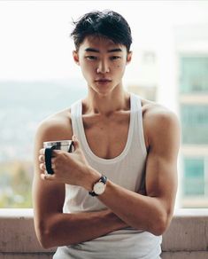 a young man holding a cup and looking at his watch