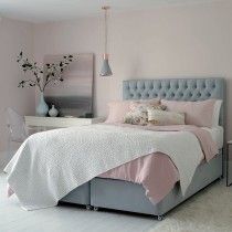 a bedroom with pink walls and white carpeted flooring, a gray bed frame has an upholstered tufted headboard