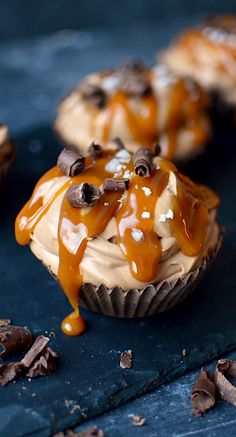 chocolate cupcakes with caramel sauce drizzled over them on a blue surface