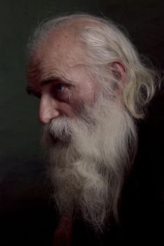 an old man with long white hair and beard in the dark looking into the distance