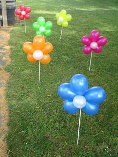 several balloons are placed in the grass with flowers on them and one balloon is floating