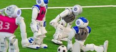 three robots are playing soccer on the field