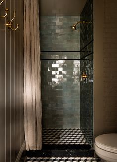 a bathroom with black and white tiles on the floor, shower curtain, and toilet