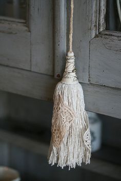 a white tassel hanging from the side of a door with an old window in the background