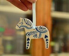 a hand holding a white and blue ceramic horse ornament on a wooden pole