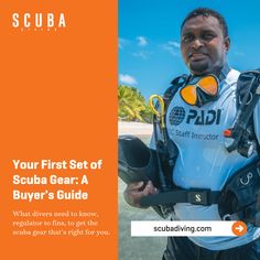 a man in scuba gear standing on the beach with an orange and white banner behind him