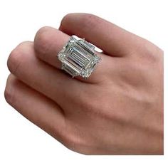 a person's hand holding a ring with an emerald stone in the center and two baguettes on each side