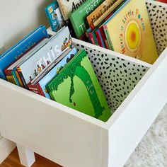 a white wooden box filled with books on top of a floor