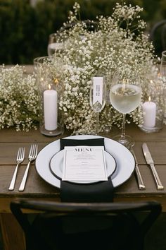 a table set with white flowers and silverware for an elegant wedding reception in the garden