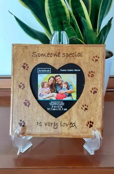 a wooden frame with a dog's paw prints and a heart shaped photo on it