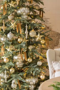 a decorated christmas tree with gold and silver ornaments on it's branches in front of a map