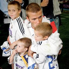 a man holding two small boys in his arms